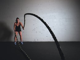 Eine Frau im Fitnessstudio trainiert an Seilen.