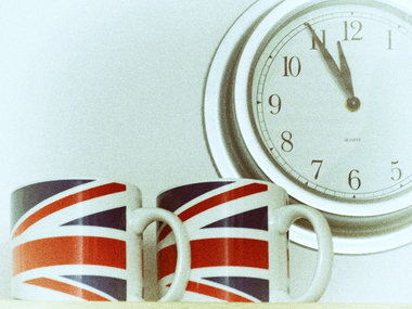 Zwei Tassen mit einer Englandflagge und einer Uhr, die fünf vor zwölf anzeigt.