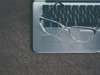 Eine Brille liegt auf dem Rand eines Computers.