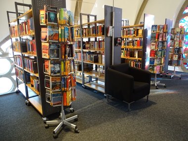 Ausgestellte Bücher in der Bücherei in zahlreichen Regalen mit einem schwarzen Sessel.