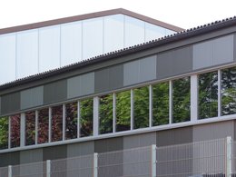 Langes grauer Industrie-Bürogebäude mit Blechverkleidung und vielen Fenster.