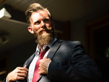 Ein Mann mit Anzug, roter Krawatte und Bart.