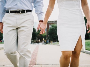 Ein Mann und eine Frau gehen Hand in Hand auf einer Straße in einer Stadt.
