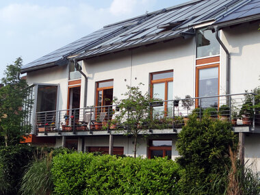 Das Bild zeigt ein Wohnhaus mit vielen grünen Pflanzen, das das Thema der umweltfreundlichen Wärmepumpen symbolisiert.
