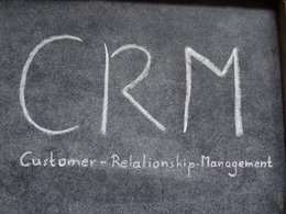 Auf einer Tafel stehen mit Kreide die Buchstaben CRM: Customer-Relationship-Management geschrieben.