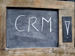 Auf einer kleinen Tafel stehen mit Kreide die Buchstaben CRM für Customer-Relationship-Management geschrieben.