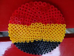 Ein Kreis aus Bügelperlen mit den Farben der Deutschlandflagge und rotem Hintergrund.