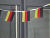 Eine Wimpelkette mit Deutschlandfähnchen vor einer grauen Haustür.