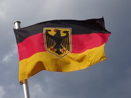 Eine Deutschlandfahne mit dem schwarzen Adler flattert vor grauem Himmel.