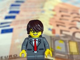BDU-Studie „Vergütung in der Unternehmensberatung 2014/2015“:  Ein Legomännchen im Anzug mit Geldscheinen symbolisiert das Thema Consulting-Gehälter.
