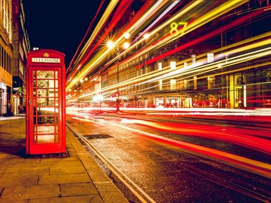 Eine englische, rote Telefonzelle mit einer Straße mit Lichteffekten.