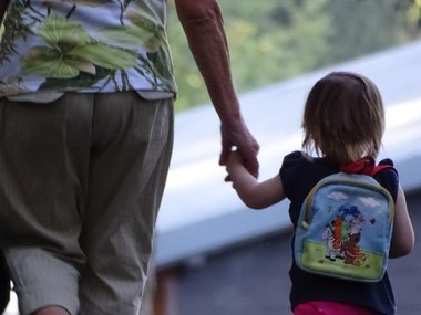 Demografie: Eine Oma geht mit ihrem Enkelkind Hand in Hand spazieren.Man sieht die beiden von hinten.