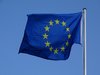 Blaue-Karte der EU: Fahne der Europäischen Union flattert vor blauem Himmel im Wind.