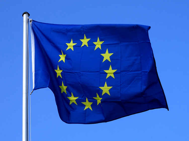 Eine Fahne der Europäischen Union flattert am blauen Himmel im Wind.