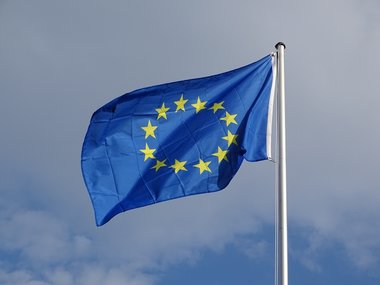 Die Flagge der Europäischen Union flattert vor grauem Himmel im Wind.