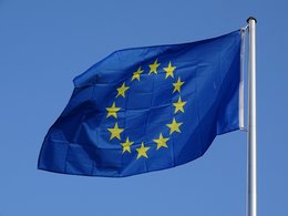 Studierenden in Europa: Die EU-Flagge vor blauem Himmel im Sonnenschein.