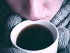 Fehltage: Eine krankgeschriebene Mitarbeiterin nippt an einer Tasse heißem Tee.