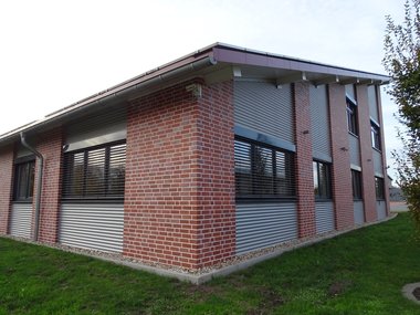 Ein neu gebautes Firmenhaus mit rotem Backstein und heruntergelassenen Jalousien.