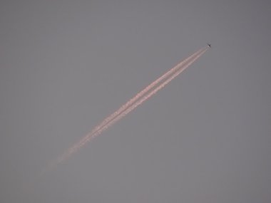 Ein steil aufsteigendes Flugzeug mit einem rotem Schweif.