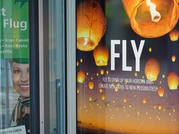 Ein Werbeplakat mit Leuchten und der großen, weißen Schrift: Fly.