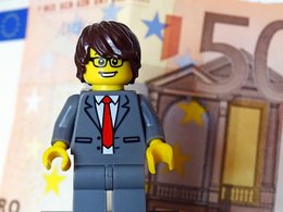 Ein Lego-Männchen im Anzug mit vielen 50 Euro Scheinen symoblisiert das Thema Gehalt.