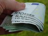 Ein Hand hält ein Bündel 100 Euro Geldscheine.