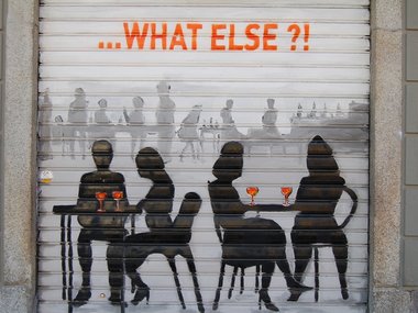 Ein Gemälde an einer geschlossenen Garage von Menschen, die in einer Kneipe sitzen und der Schrift:...what else?!