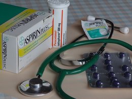 Tabletten, ein Stetoskop und Aspirin liegen zusammen auf einem Tisch.