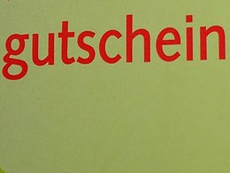 Eine Pinnwand mit Gutscheinen z.B. einen grünen Aktionsgutschein und einen von einem Restaurant mit Namen Brandenburger Tor.