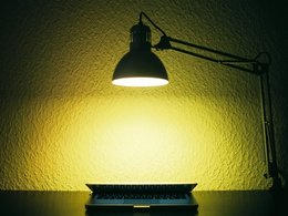 Hacker: Eine Schreibtischlampe brennt nachts hell über einen halb geöffneten Notebook.