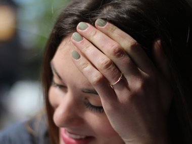 Eine Hand mit grünen Fingernägeln stützt einen Frauenkopf.