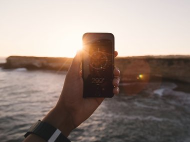 Ein Handy wird von einer Hand in die Luft gehalten und zeigt ein Bild von einer Kompass-App.