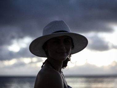 Eine Frau mit Hut am Strand.