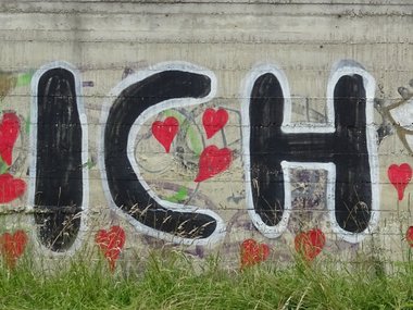 Ein Ich-Liebe-Dich Graffiti und eine Herz mit Flügeln an einer Mauer.