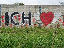 Ein Ich-Liebe-Dich Graffiti und eine Herz mit Flügeln an einer Mauer.