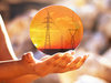 innogy Consulting: Händer halten eine Seifenblase, in der ein Stromnetz bei Sonnenaufgang zu sehen ist. 