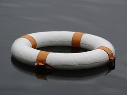 Ein weißer Schwimmrettungsring mit orangenen Streifen auf dem Wasser.