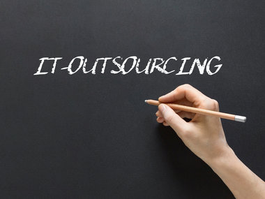 Auf einer schwarzen Tafel steht in weißer Schrift das Wort "IT-Outsourcing".