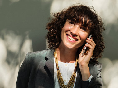 Jobzufriedenheit: Eine weibliche Führungskraft lacht beim Telefonieren.