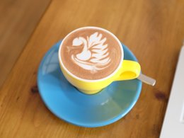 Eine bunte Kaffeetasse mit einem Muster im Milchschaum.