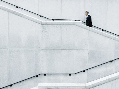 Karriere zum DAX-CEO: Eine junger Manager im Anzug läuft eine lange Treppe hoch.
