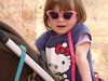 Kind und Karriere: Ein Mädchen mit pinker Sonnenbrille und einem Hello Kitty-Kleid in einem Kinderwagen.