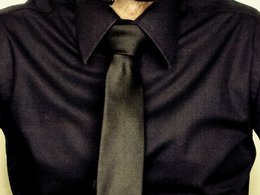 Mann mit einem schwarzen Hemd und schwarzer Krawatte.