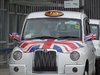 Ein weißes London-Taxi mit einer britischen Fahne auf der Motorhaube.