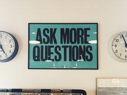 Ein grünes Schild mit der Aufschrift: Ask more questions.