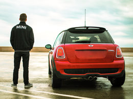 Ein Mann mit einer Jacke mit der Aufschrift: Mini steht neben einem Auto derselben Marke.