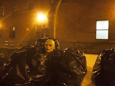 Der Kopf einer Modepuppe steht zwischen schwarzen Müllbeuteln.
