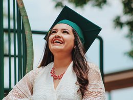 Eine Absolventin mit Graduation Cap freut sich über Ihren Studienabschluss bei einem Studium im Ausland..