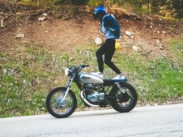 Ein Mann mit Helm, der auf seinem Motorrad steht.