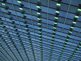 Zahlreiche grüne Lampen bilden ein identisches Muster unter einer Gebäudedecke.